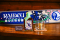 U products Raidou collection: Japanese pepper and yuzu cola, glow in the dark bottle seal, mat, rock glass, and bonus Shin Sekai matchbox (U Products, 2025)